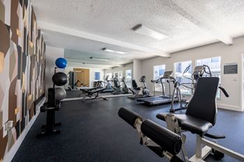A gym with weights and other exercise equipments in a room with a large window